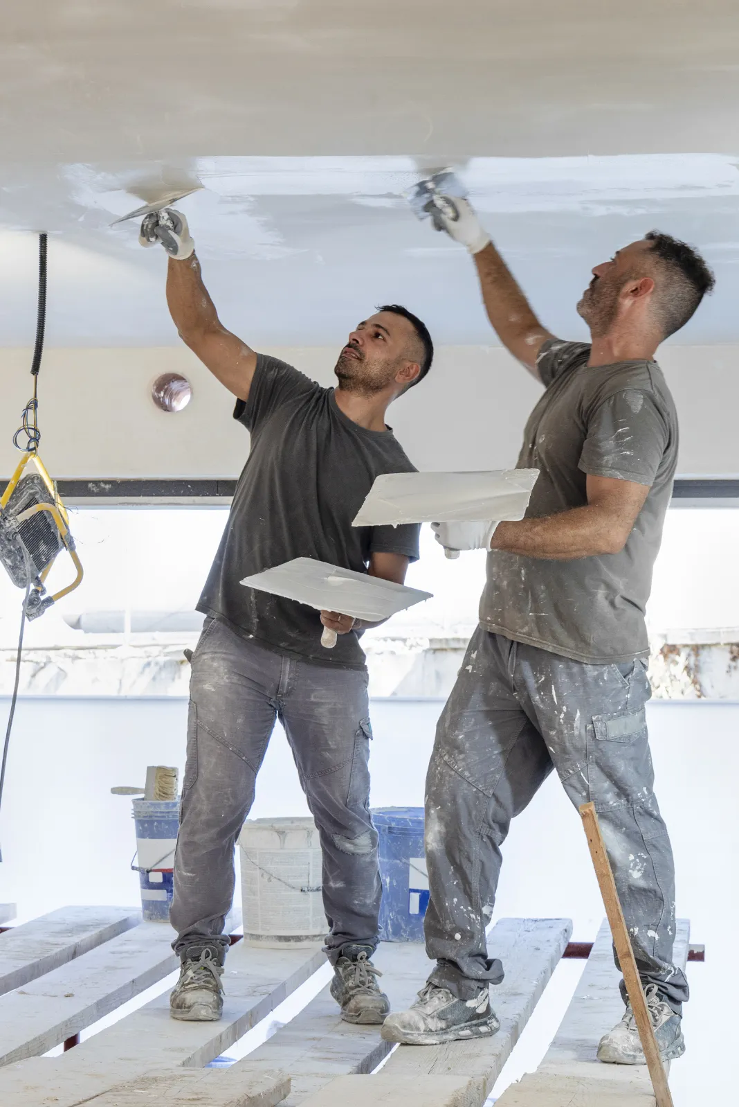 Remodeling execution in Los Angeles with workers applying ceiling finish during construction