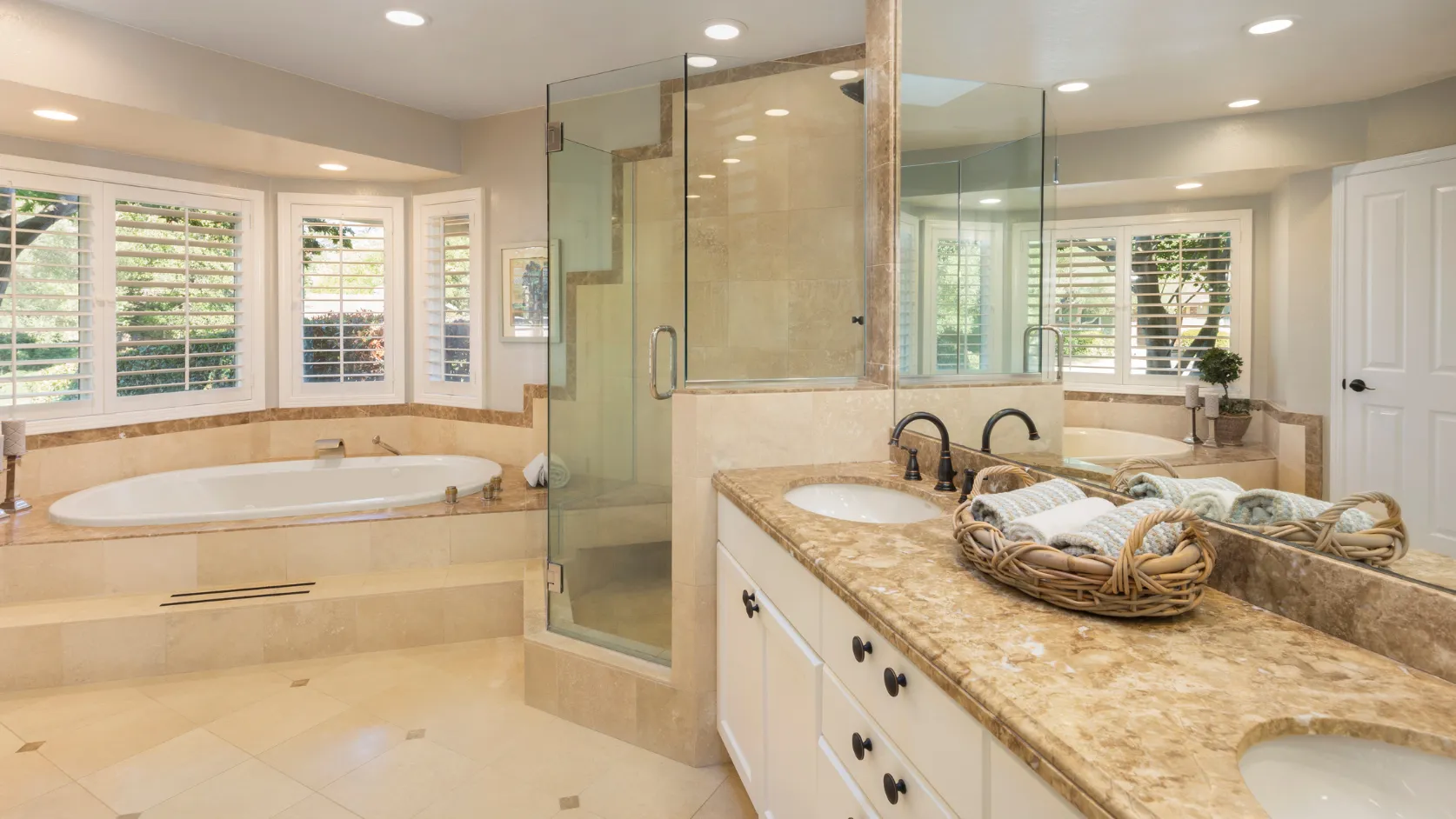 After bathroom remodeling project in Los Angeles with modern vanity, glass shower, bathtub, stone counters, recessed lighting, and premium tile finishes