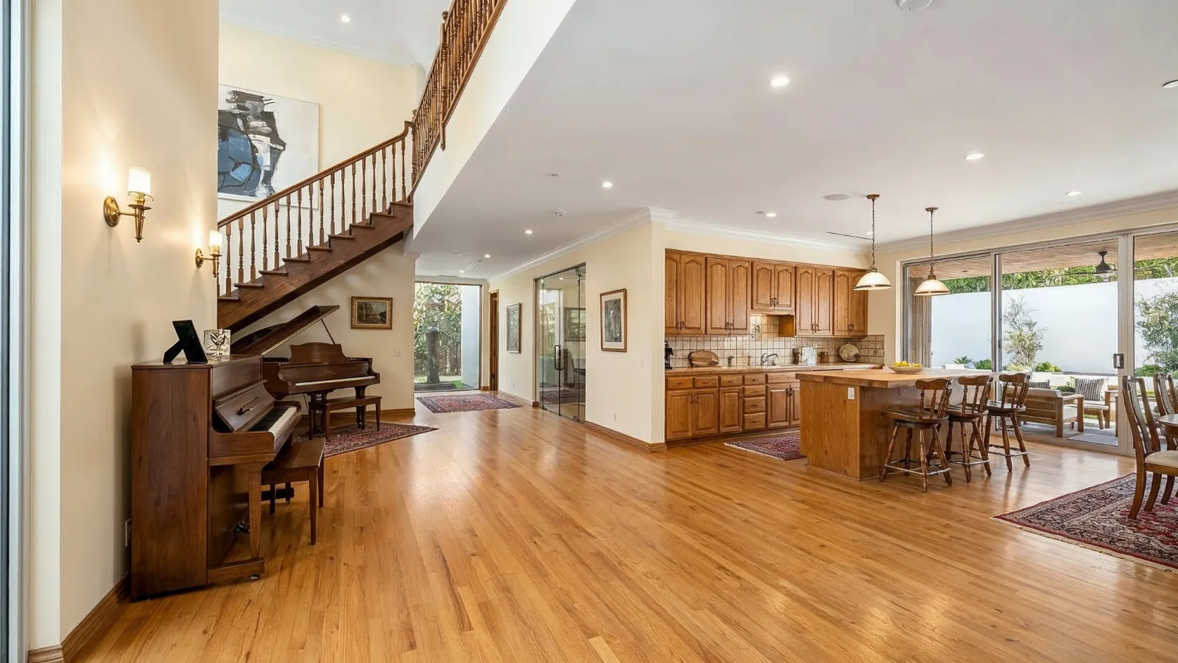 Before interior remodeling project in Los Angeles with traditional staircase, older wood kitchen cabinets, dated flooring, and classic interior finishes
