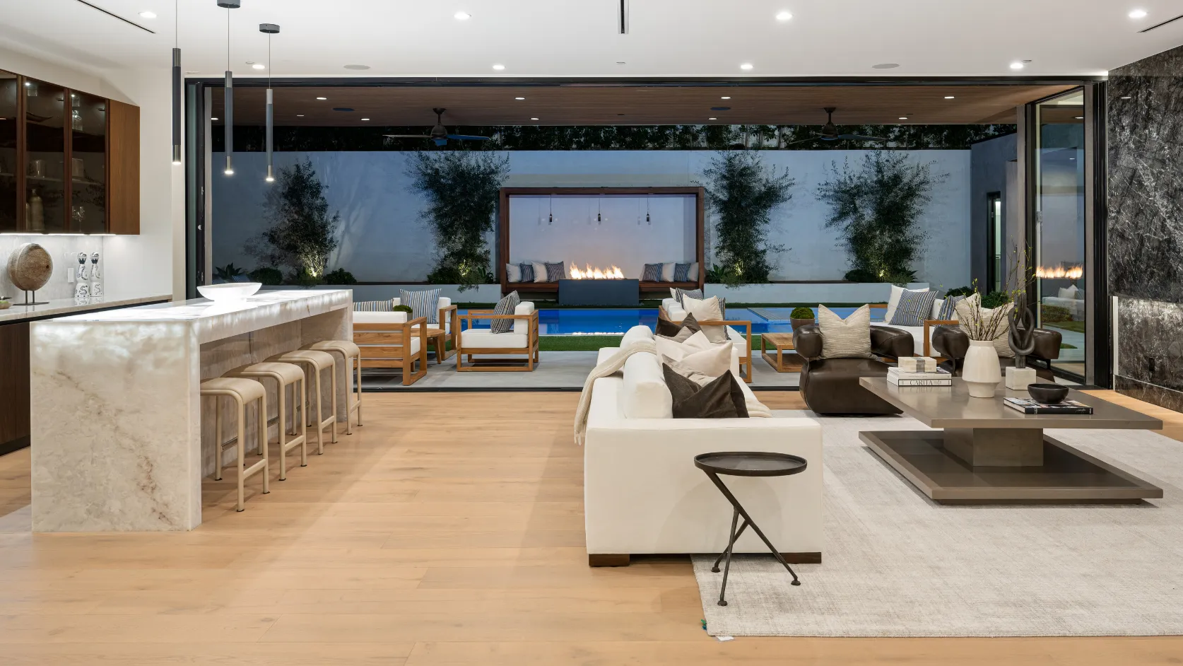 After luxury home remodeling project in Los Angeles with high-end indoor outdoor living area, marble bar, modern seating, pool view, premium lighting, and elegant finishes