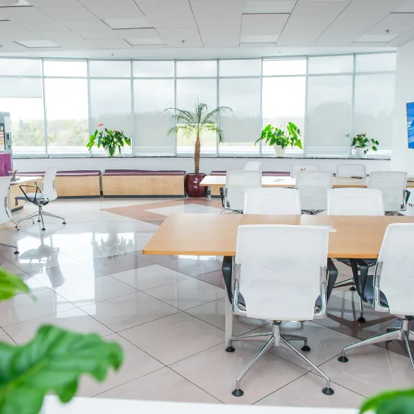 Office remodeling project in Los Angeles with bright conference room, large windows, modern tables, white chairs, polished flooring, and professional workspace design