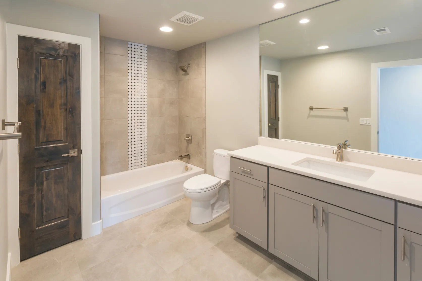 Completed bathroom remodeling project in Los Angeles with modern vanity, bathtub, shower tile, large mirror, recessed lighting, and premium finishes