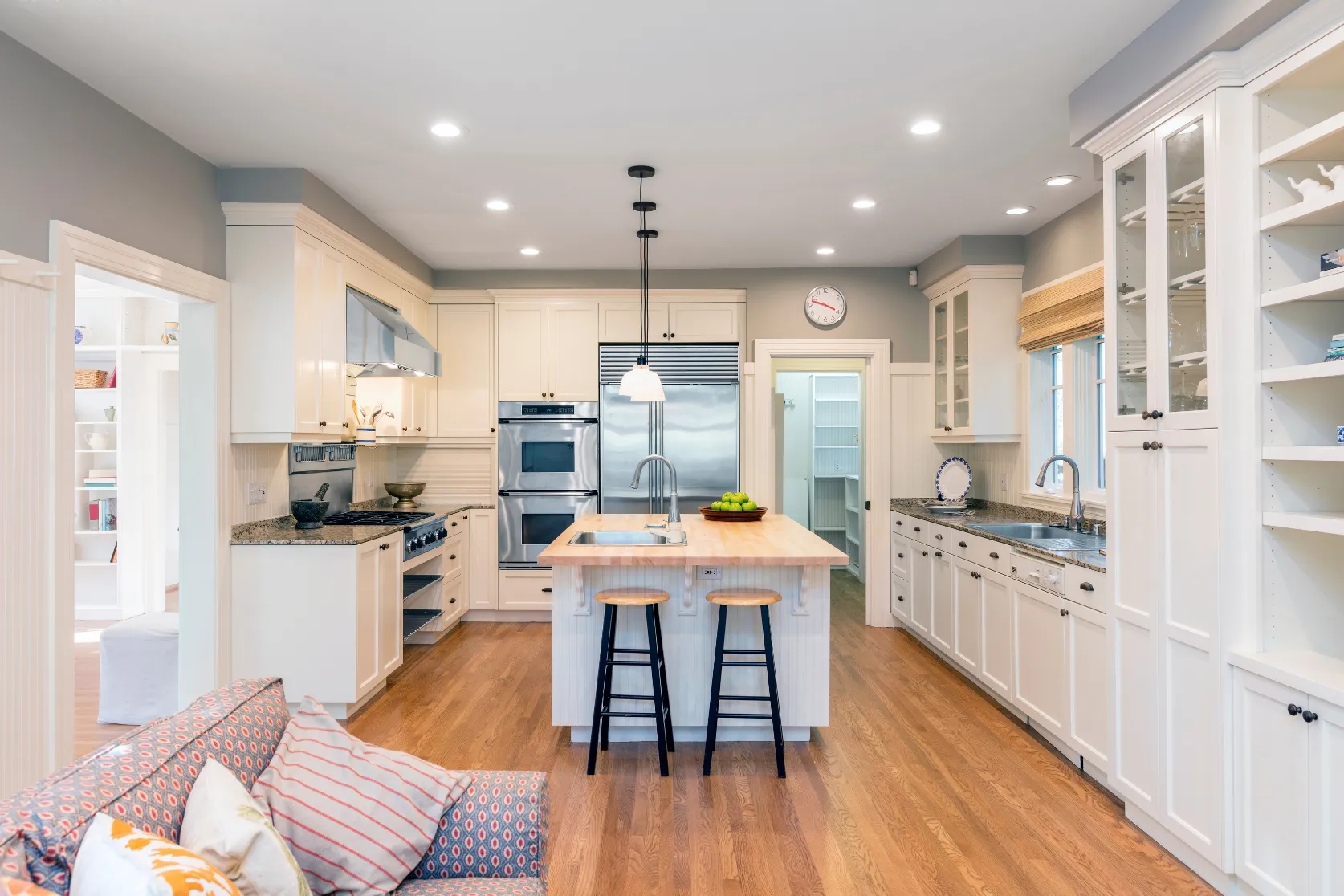 Completed kitchen remodeling project in Los Angeles with white custom cabinets, center island, recessed lighting, hardwood flooring, and premium finishes