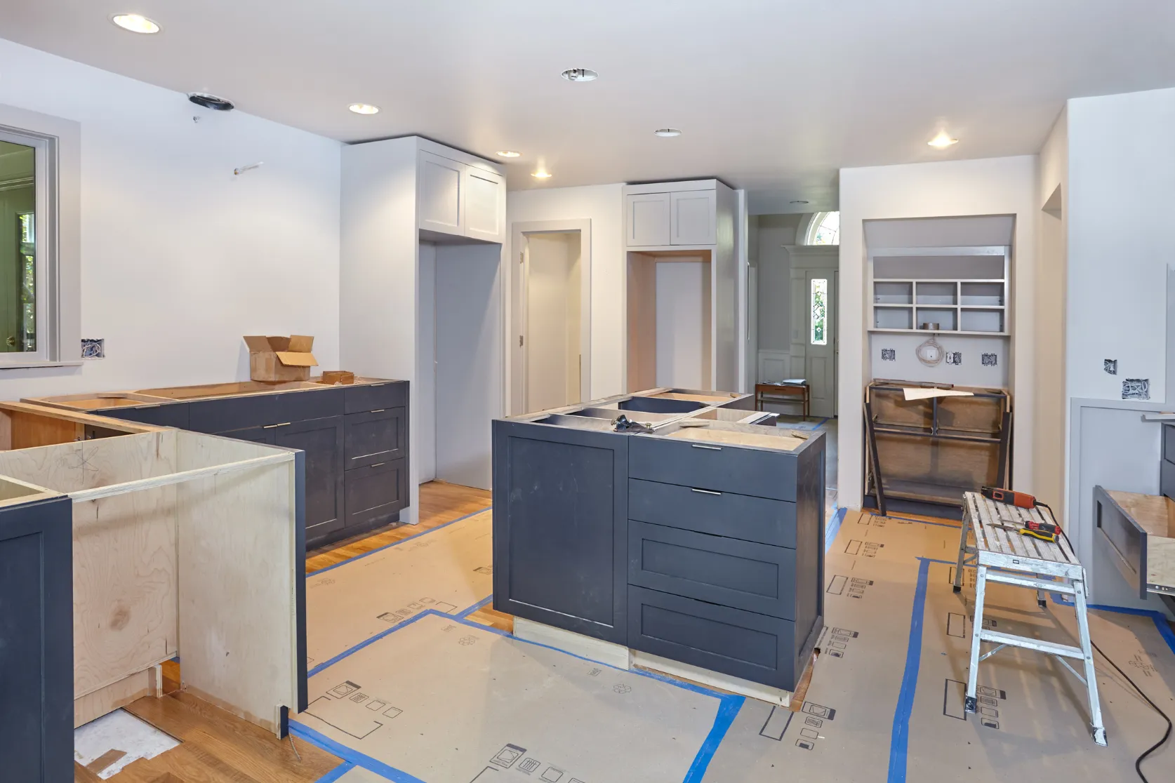 Los Angeles kitchen remodeling project with dark cabinet installation, island buildout, protected flooring, lighting upgrades, and finish preparation
