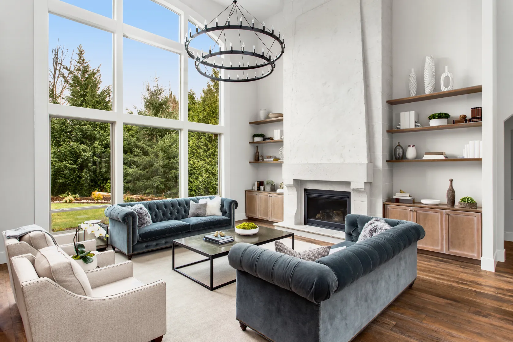 Completed luxury home remodeling in Los Angeles with elegant living room, floor-to-ceiling windows, custom fireplace, hardwood flooring, chandelier, and built-in shelving