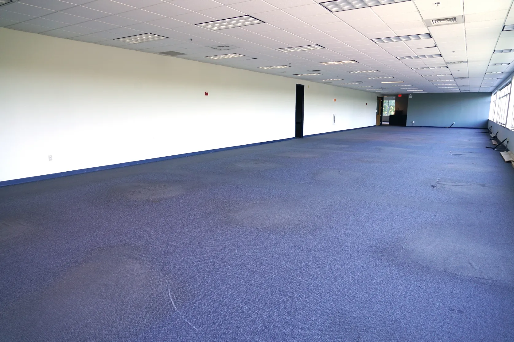 Completed office remodeling in Los Angeles with open commercial workspace, updated carpet flooring, drop ceiling, lighting, and clean interior finishes